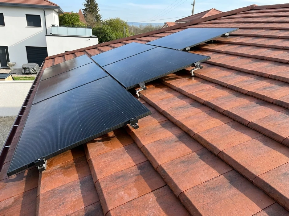Toiture en tuiles romanes rouge-brique avec installation de panneaux solaires photovoltaïques monocristallins noirs