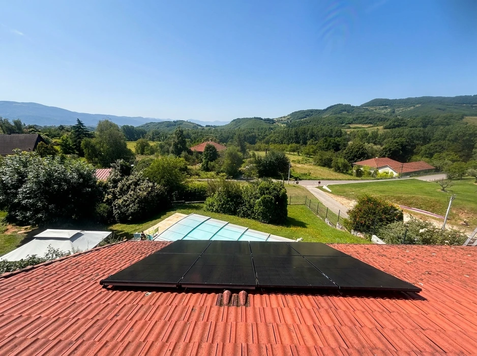 Vue aérienne d'une installation photovoltaïque en toiture, composée de 6 panneaux solaires monocristallins full black disposés en 2 rangées de 3, montés sur tuiles canal rouges