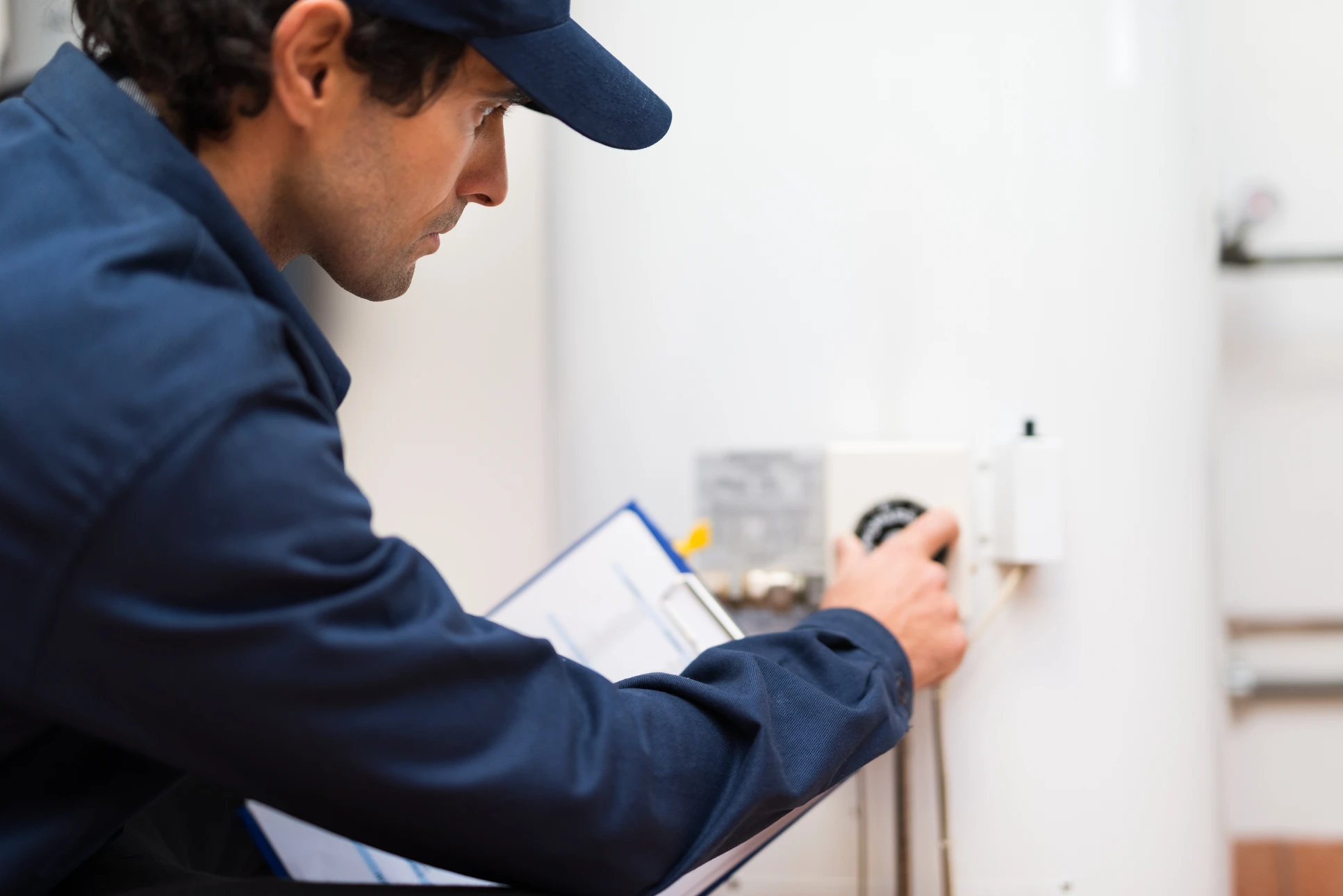 Technicien en uniforme bleu effectuant une intervention sur chauffe-eau domestique