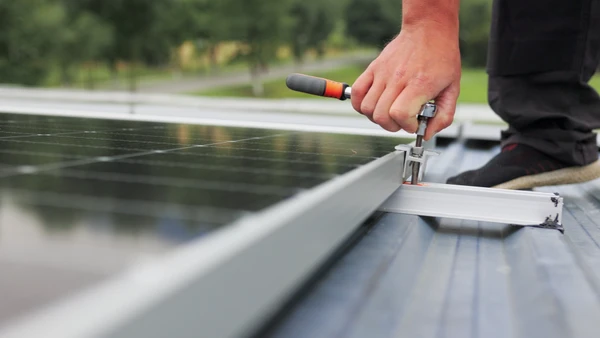 Des techniciens montent des modules photovoltaïques sur le toit de la maison