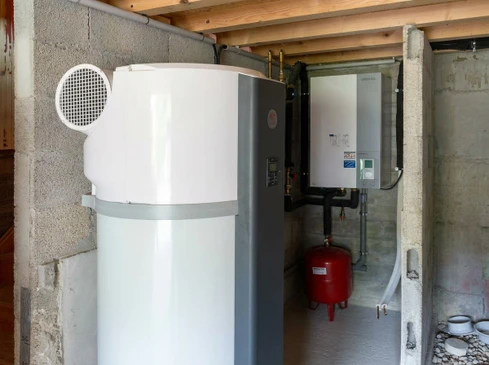 Toiture r&eacute;sidentielle &eacute;quip&eacute;e de quatre chauffe-eau solaires thermiques install&eacute;s sur tuiles rouges, ciel bleu d&eacute;gag&eacute; en arri&egrave;re-plan avec maisons voisines visibles